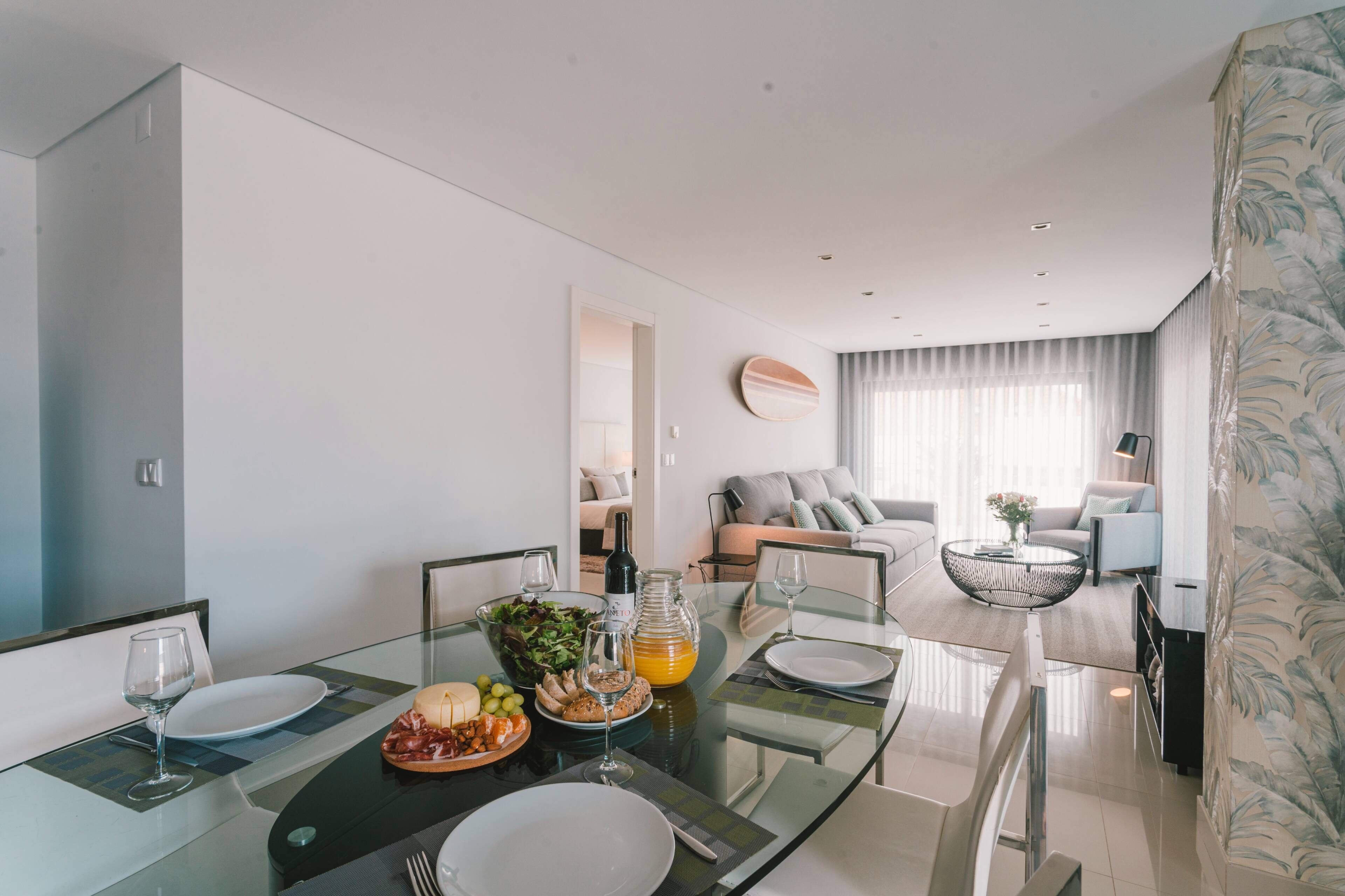 A modern living room with a glass dining table, a sofa, and a coffee table.