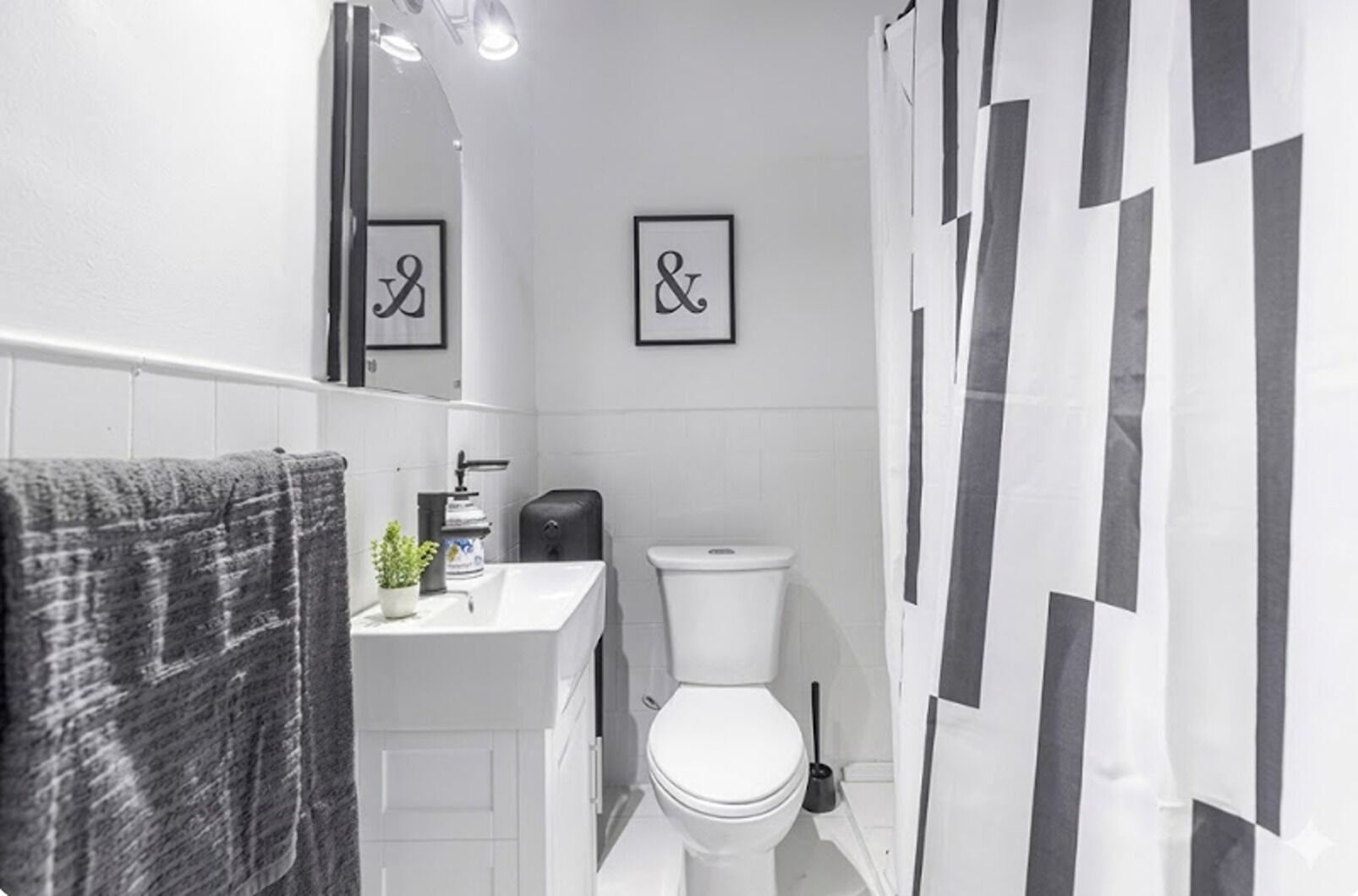 A bathroom with a white sink, toilet, and a towel rack with a towel. There are two framed pictures on the wall.