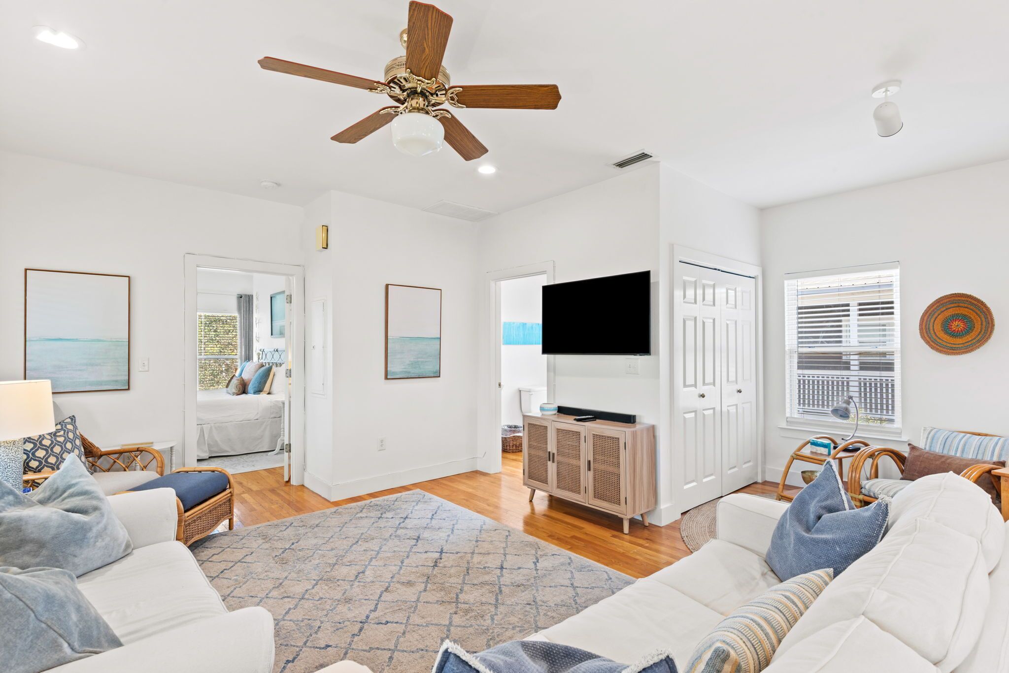 A spacious living room with a ceiling fan, a television, and a large window.