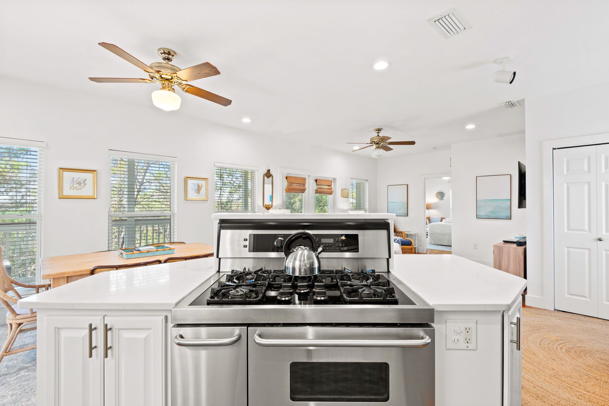 A modern kitchen with a central island, stainless steel appliances, and ceiling fans.