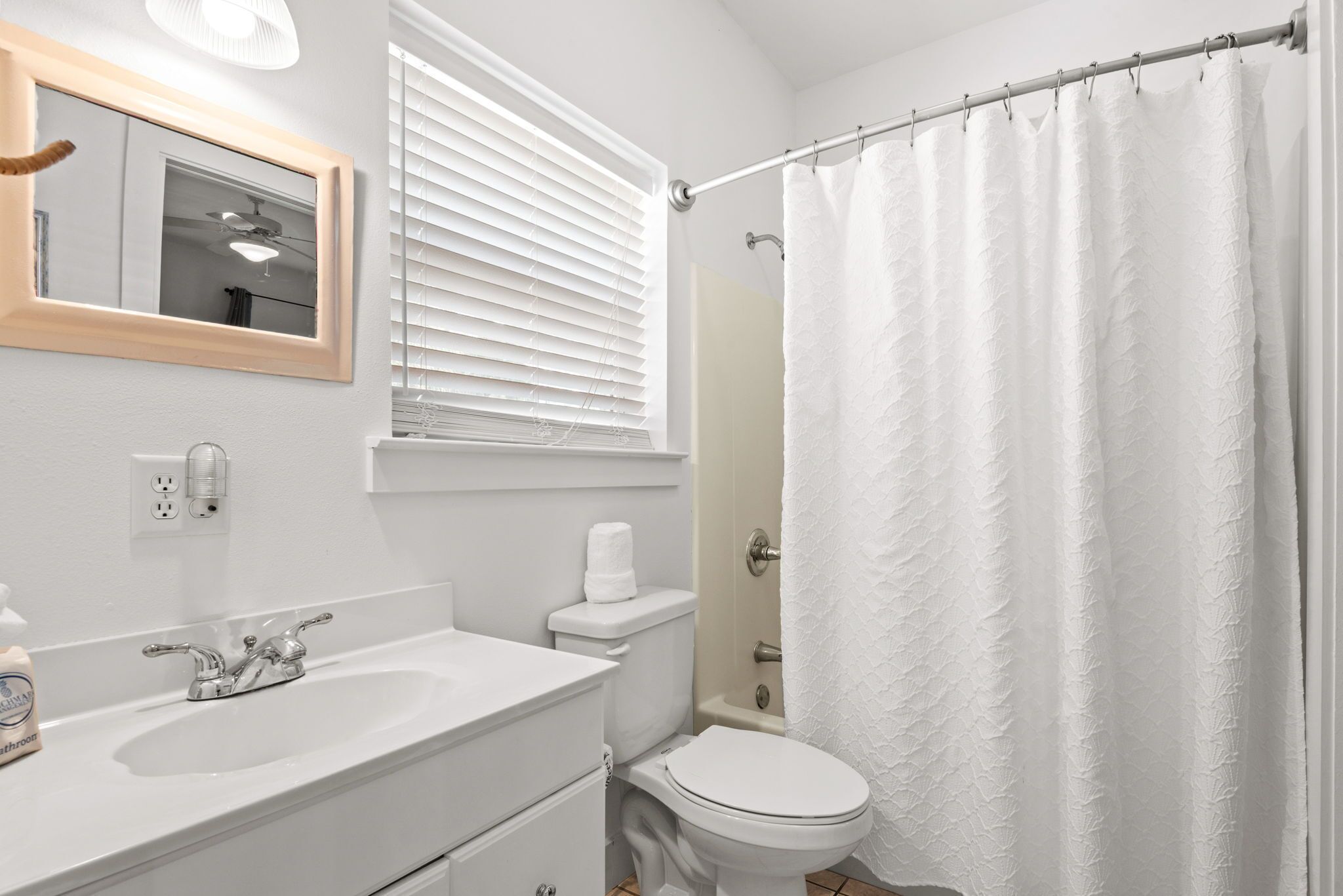 Een badkamer met een wit wastafelmeubel, toilet en douchegordijn.