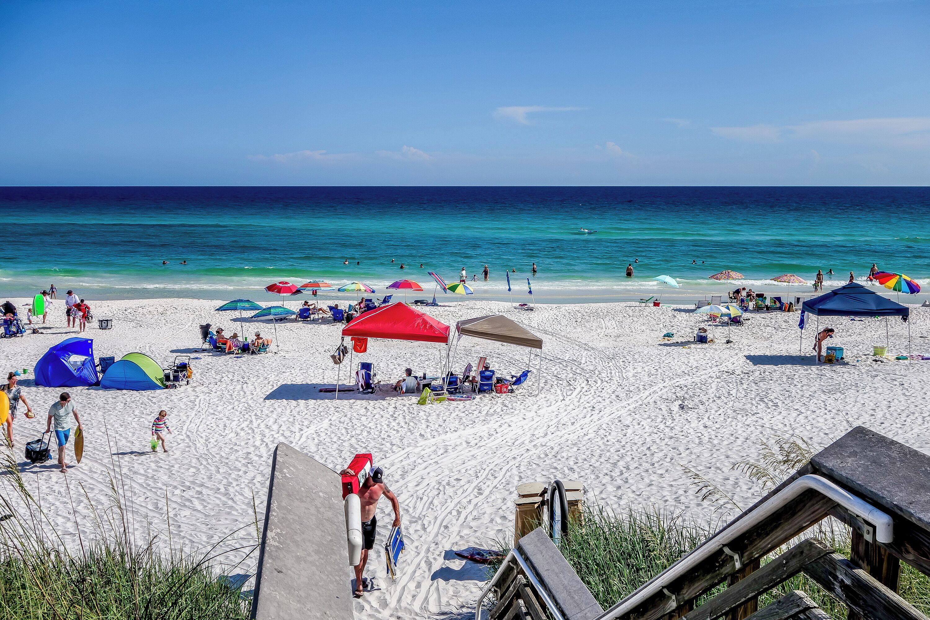 Une plage avec des parasols, des tentes et des gens.