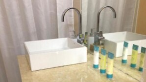 A bathroom with a white sink, two faucets, and a wooden vanity. - Cozy 1-Bedroom Studio in the Heart of Enchanting Rodney Bay–Fully AirConditioned (Rodney Bay)