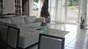A living room with a white sofa, a glass coffee table, and a Christmas tree. - Cozy 1-Bedroom Studio in the Heart of Enchanting Rodney Bay–Fully AirConditioned (Rodney Bay)