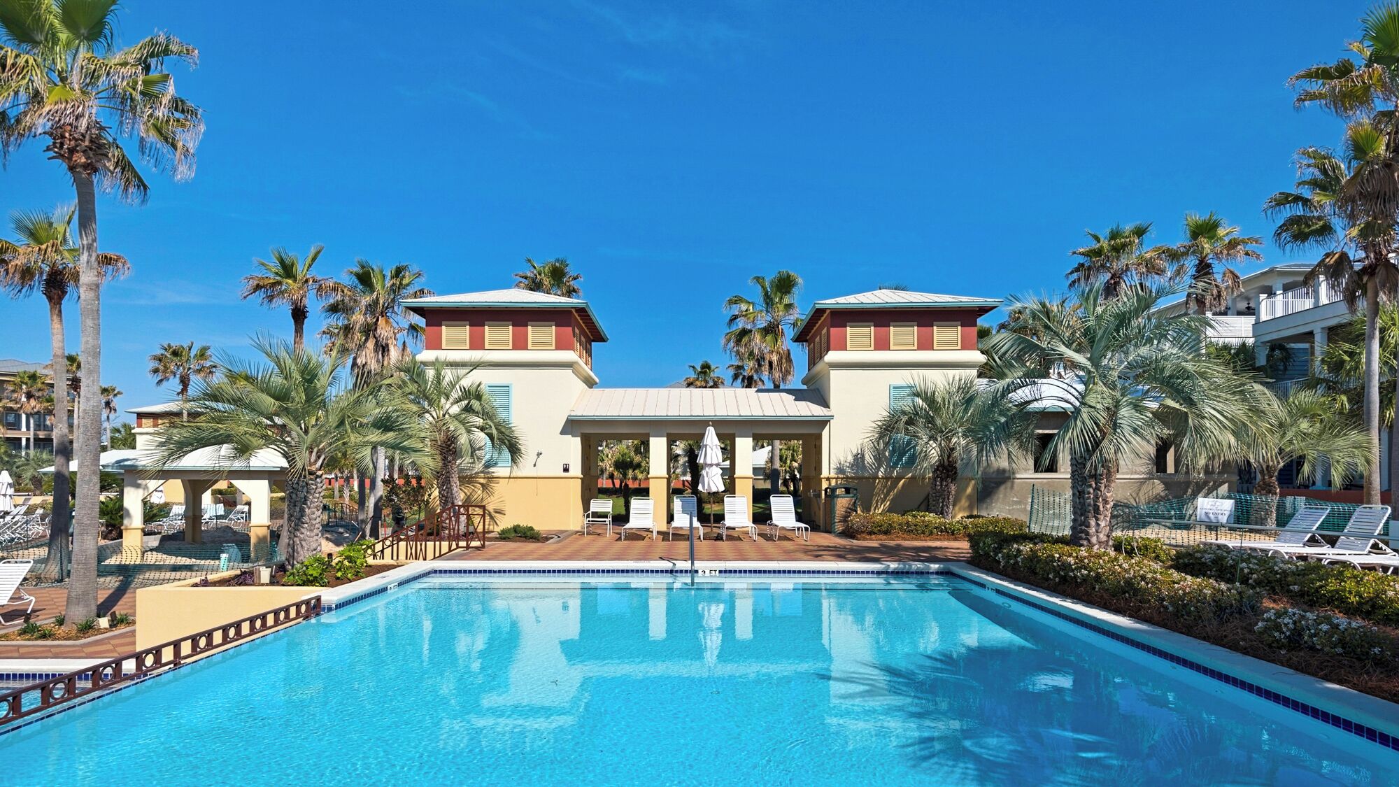 Ein Swimmingpool mit Liegestühlen und Palmen.