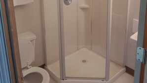 Une cabine de douche fermée par des parois de verre, avec une serviette blanche accrochée à la poignée de la porte.