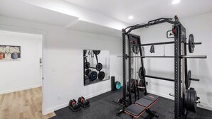 Ein Fitnessraum mit Squat-Stange, Langhantel, Gewichte und einer Trainingsbank.