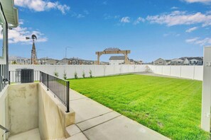 A residential area with a well-maintained lawn, a windmill in the distance, and a clear sky. - Lehi Basement: 2 Kings, 4 Queens, Pool & Parks (Lehi)
