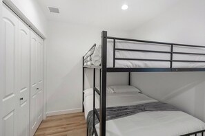 A bunk bed with a white mattress and gray blanket, a white wardrobe with multiple doors, and a wooden floor. - Lehi Basement: 2 Kings, 4 Queens, Pool & Parks (Lehi)