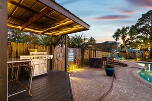 Eine Terrasse im Freien mit Grill, Sitzgelegenheiten und einem Pool.