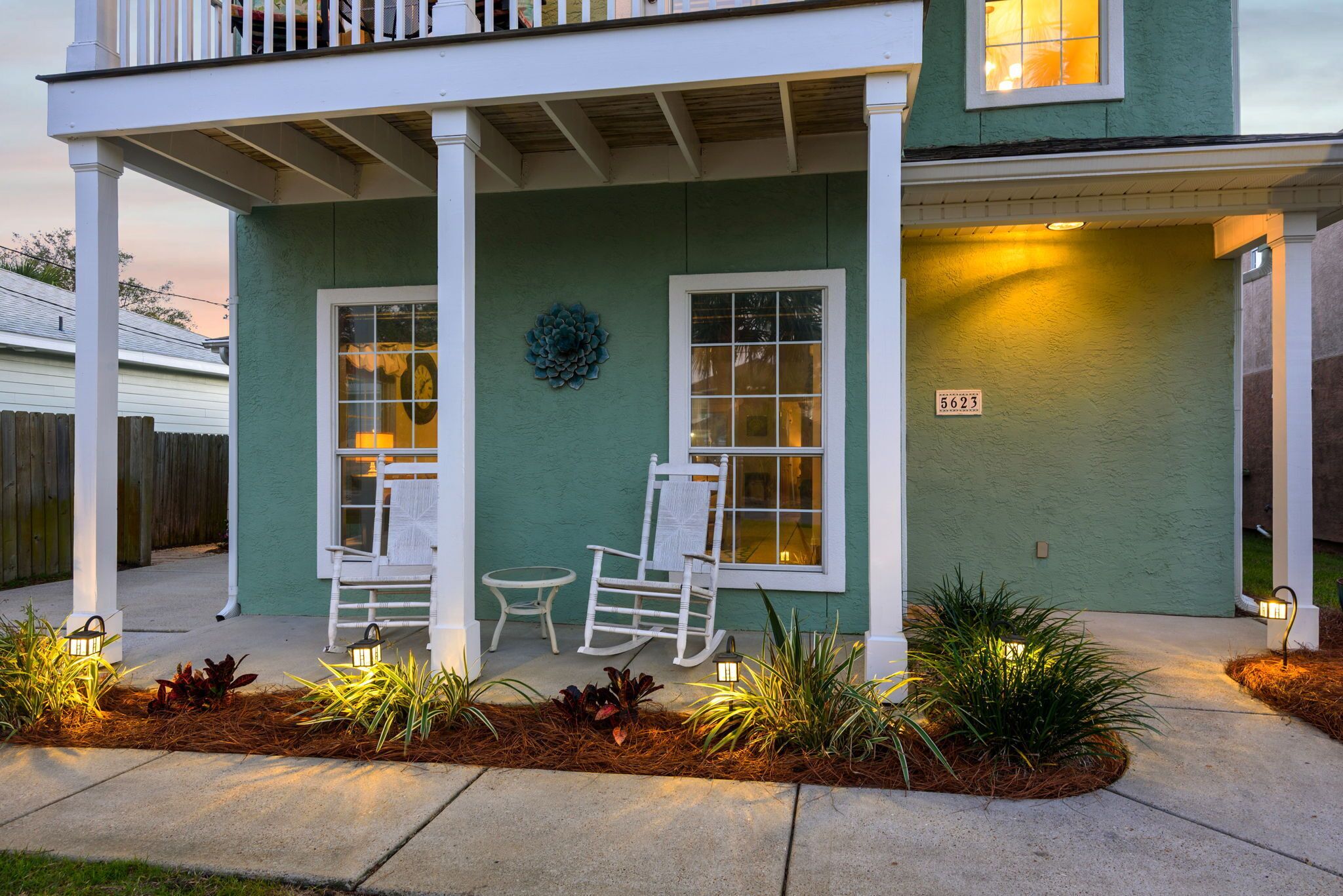 A house with a porch, two rocking chairs, a small table, and a mailbox.