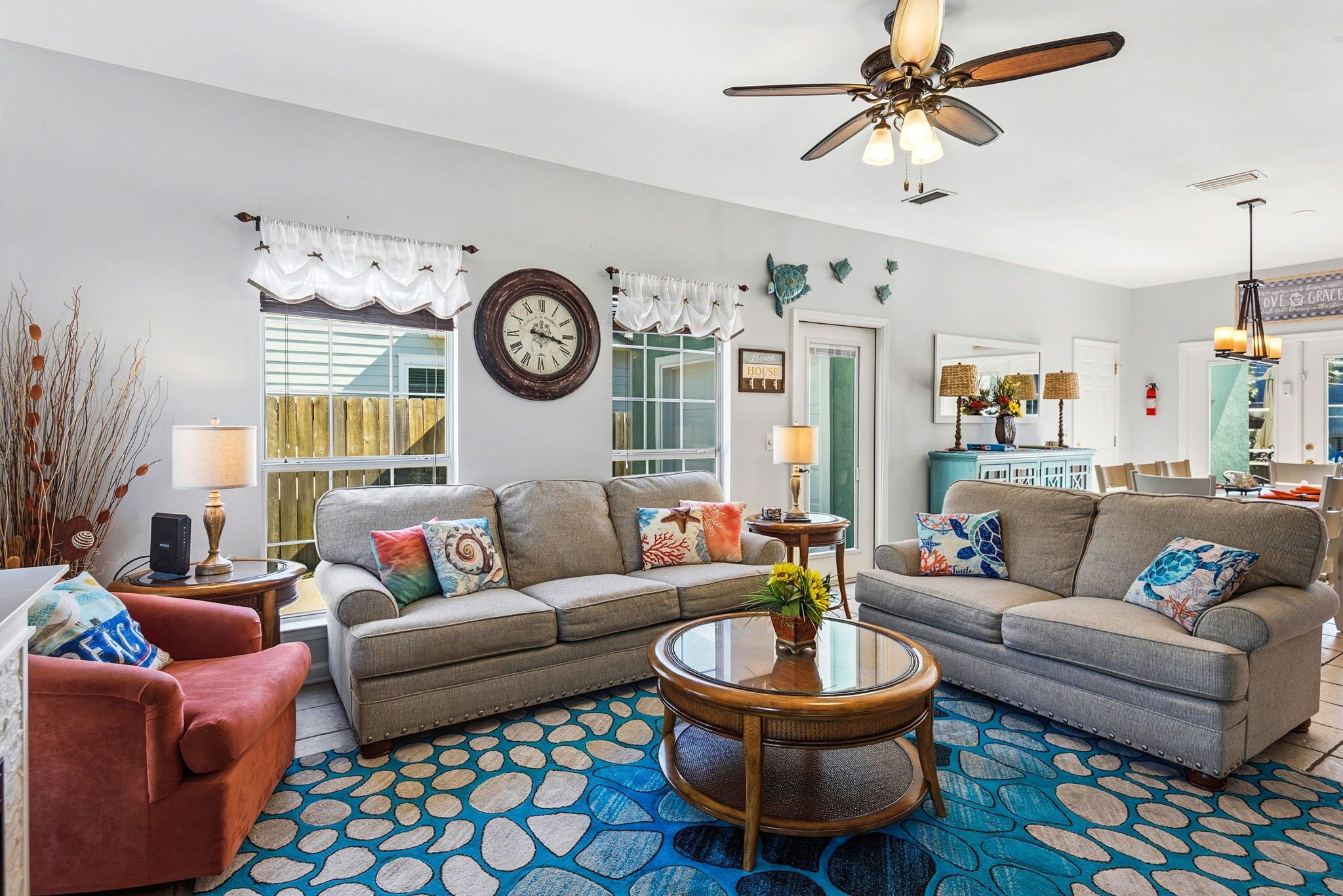 A living room with a sofa, armchairs, a coffee table, and a ceiling fan.
