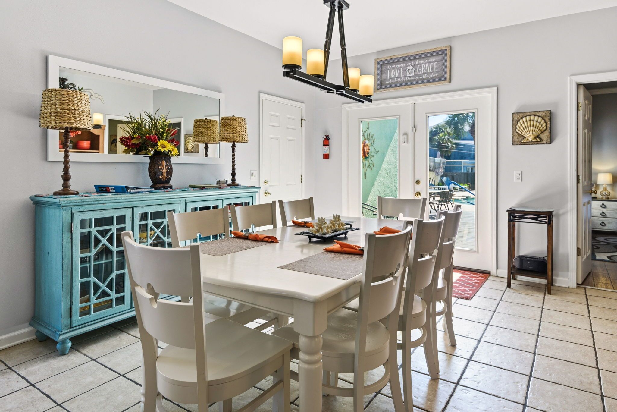 A dining area with a white table, chairs, a blue cabinet, and a chandelier.