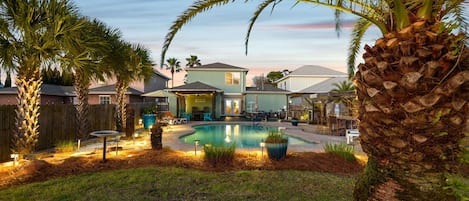 A residential area with a swimming pool, palm trees, and houses in the background.