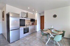 A modern kitchen with stainless steel appliances, a dining table with four chairs, and a small decorative plant. - Le Dolce Verde | Downtown, beaches & parking (Ajaccio)