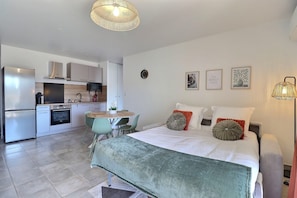 A modern bedroom with a bed, bedside tables, and a view into the kitchen. - Le Dolce Verde | Downtown, beaches & parking (Ajaccio)