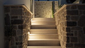 Escadaria que leva a um edifício com paredes de pedra e design moderno.
