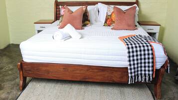 A neatly made bed with a white quilt, two wooden nightstands, and a checkered throw blanket.