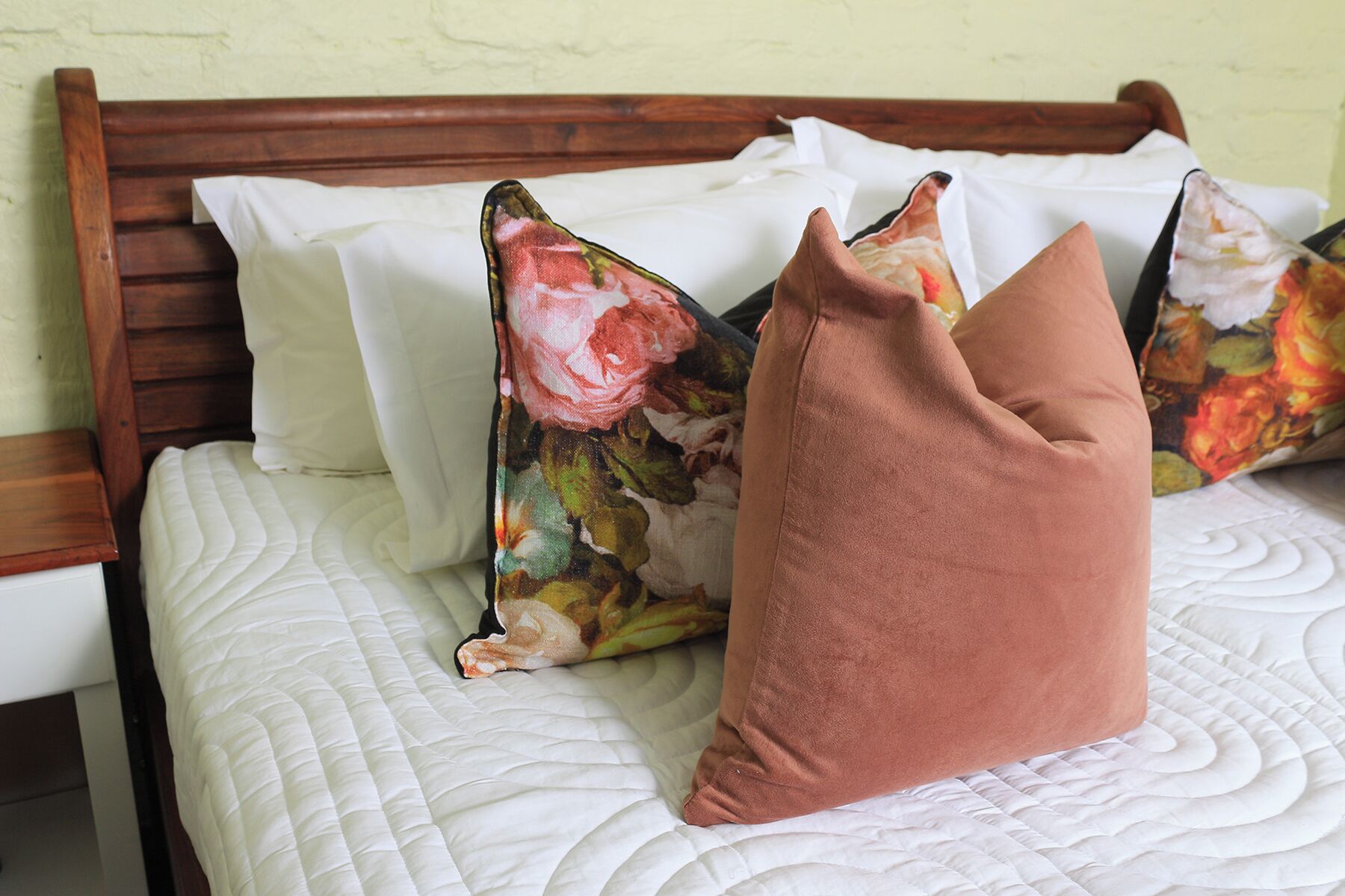 A bed with a white quilt, a wooden headboard, and decorative pillows.
