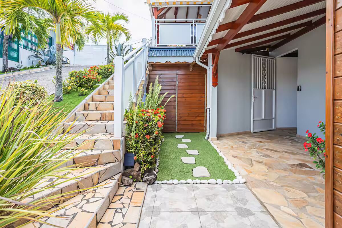 A residential property with a stone staircase, a wooden door, and a small garden area with stepping stones and plants.