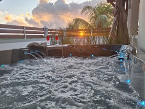 A hot tub with water jets, a control panel, and a view of the sunset and palm trees. - Villa Sun View, 3* furnished holiday home, 2 bedrooms and spa (Le Gosier)