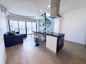 A modern kitchen with a central island, a dining area with a table and chairs, and a sofa with cushions. - Penthouse w/ Private Terrace & Tub | Rooftop Pool | Near Beach (Playa del Carmen)