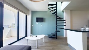 Un intérieur moderne avec un escalier en colimaçon, un téléviseur à écran plat, une petite table et une vue sur la ville grâce à de grandes fenêtres.
