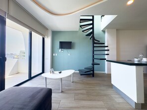 A modern interior with a spiral staircase, a flat-screen TV, a small table, and a view of the city through large windows. - Penthouse w/ Private Terrace & Tub | Rooftop Pool | Near Beach (Playa del Carmen)