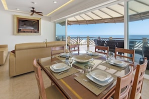 A dining area with a table set for four, a sofa, and a view of the ocean.