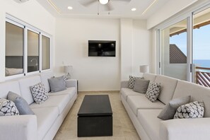 A modern living room with two sofas, a coffee table, a TV, and large windows.
