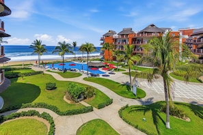 A resort with a pool area, palm trees, and a view of the ocean.