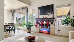 Una sala de estar moderna con chimenea, comedor y ventanas amplias.