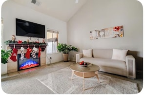 A living room with a fireplace, a sofa, a coffee table, and a flat-screen TV mounted on the wall.