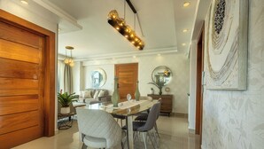 Un comedor moderno con puerta de madera, una mesa de comedor con sillas, una araña y un adorno en la pared.
