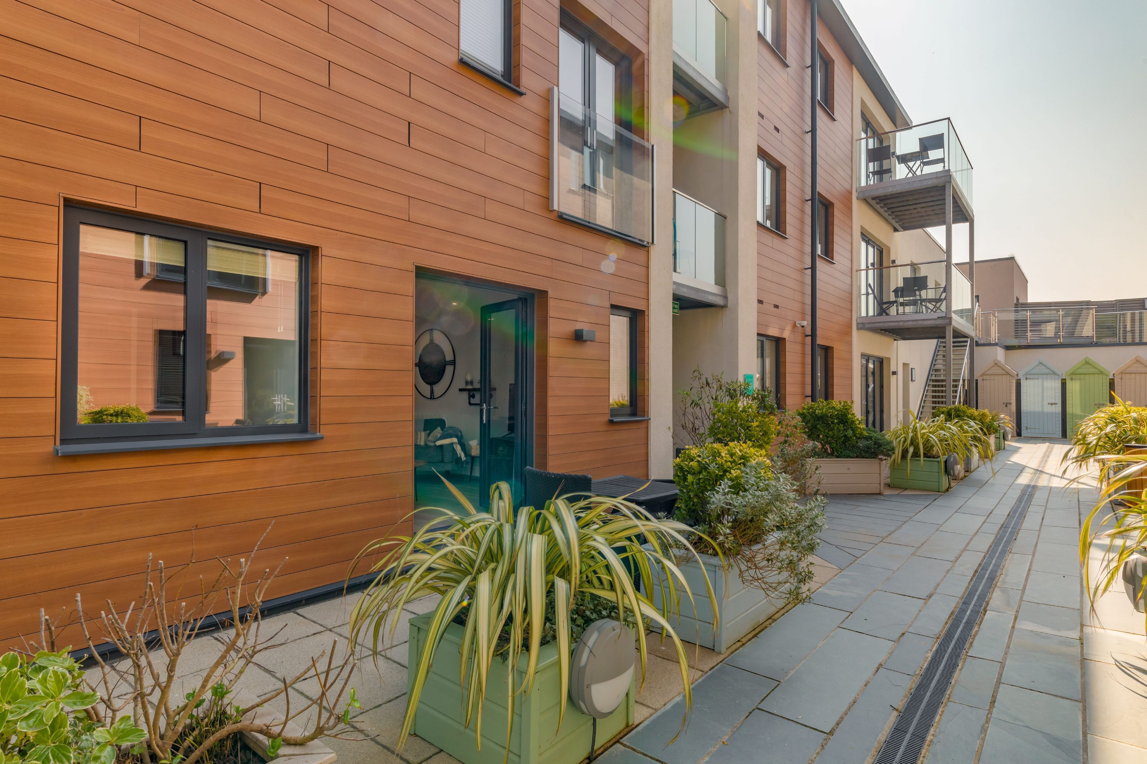 A modern building with wooden paneling, a green door, and outdoor seating.
