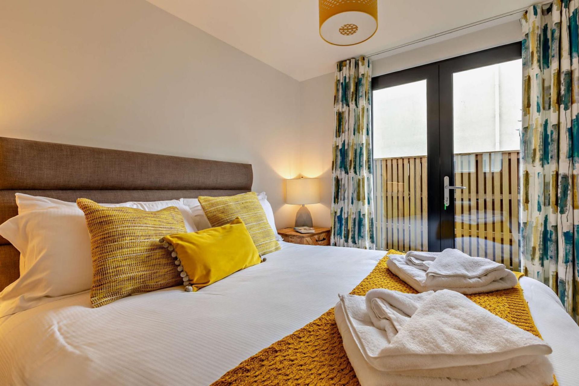Hotelkamer met een bed, kussens, een nachtkastje, een lamp en uitzicht.