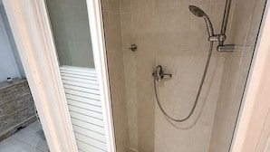 Une douche fermée par des parois en verre, dotée d’un pommeau de douche à main et d’un robinet mural.