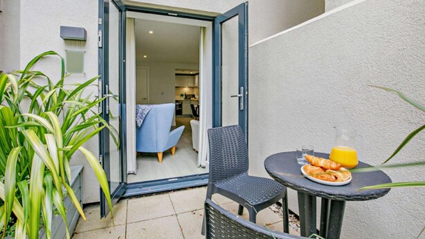 A small patio with a table, chairs, and a glass of orange juice. - Waveside - Luxury Cottages (Woolacombe)