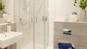 A modern bathroom with a glass-enclosed shower, a sink, and a toilet. - Reefside - Luxury Cottages (Woolacombe)