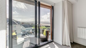 Ett rum med en stor skjutdörr i glas som leder ut till en balkong med utemöbler.