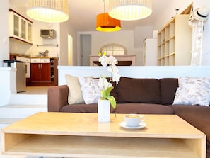 Ein modernes Wohnzimmer mit einem braunen Sofa, einem Holztisch und einer weißen Orchideen-Vase.