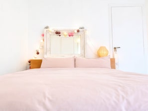Ein Schlafzimmer mit einem Bett, einem Spiegel, Lichterketten und einer Lampe.