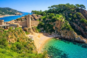 A coastal town with historic stone buildings, a beach, and clear turquoise waters. - 🏖️ Mediterranean penthouse + terrace + sea views (Canyelles)