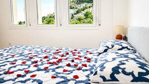 Un dormitorio con cama, vistas a una colina y una lámpara en la mesita de noche.