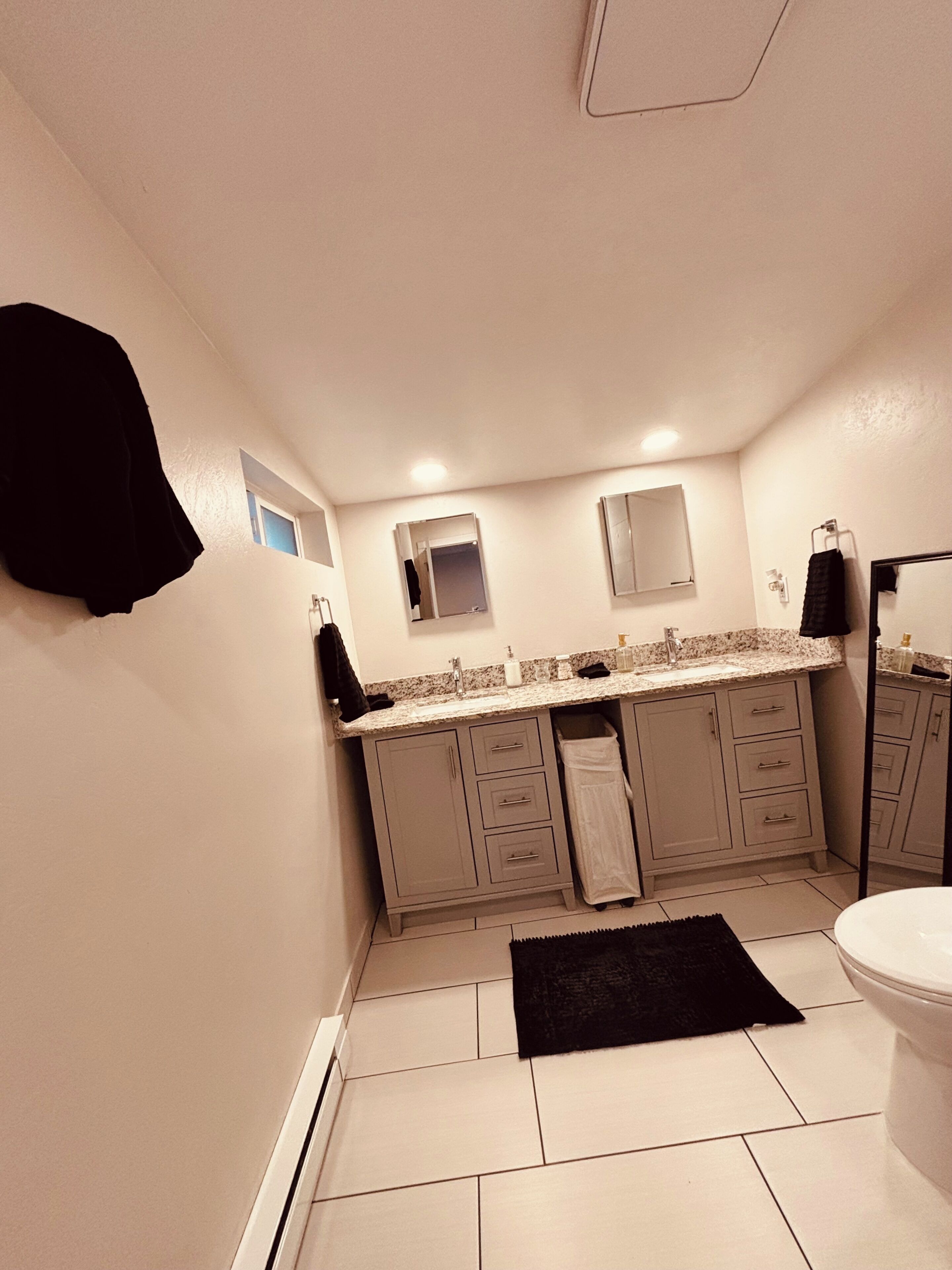 Une salle de bain comprenant des toilettes, un lavabo, un miroir et des placards.