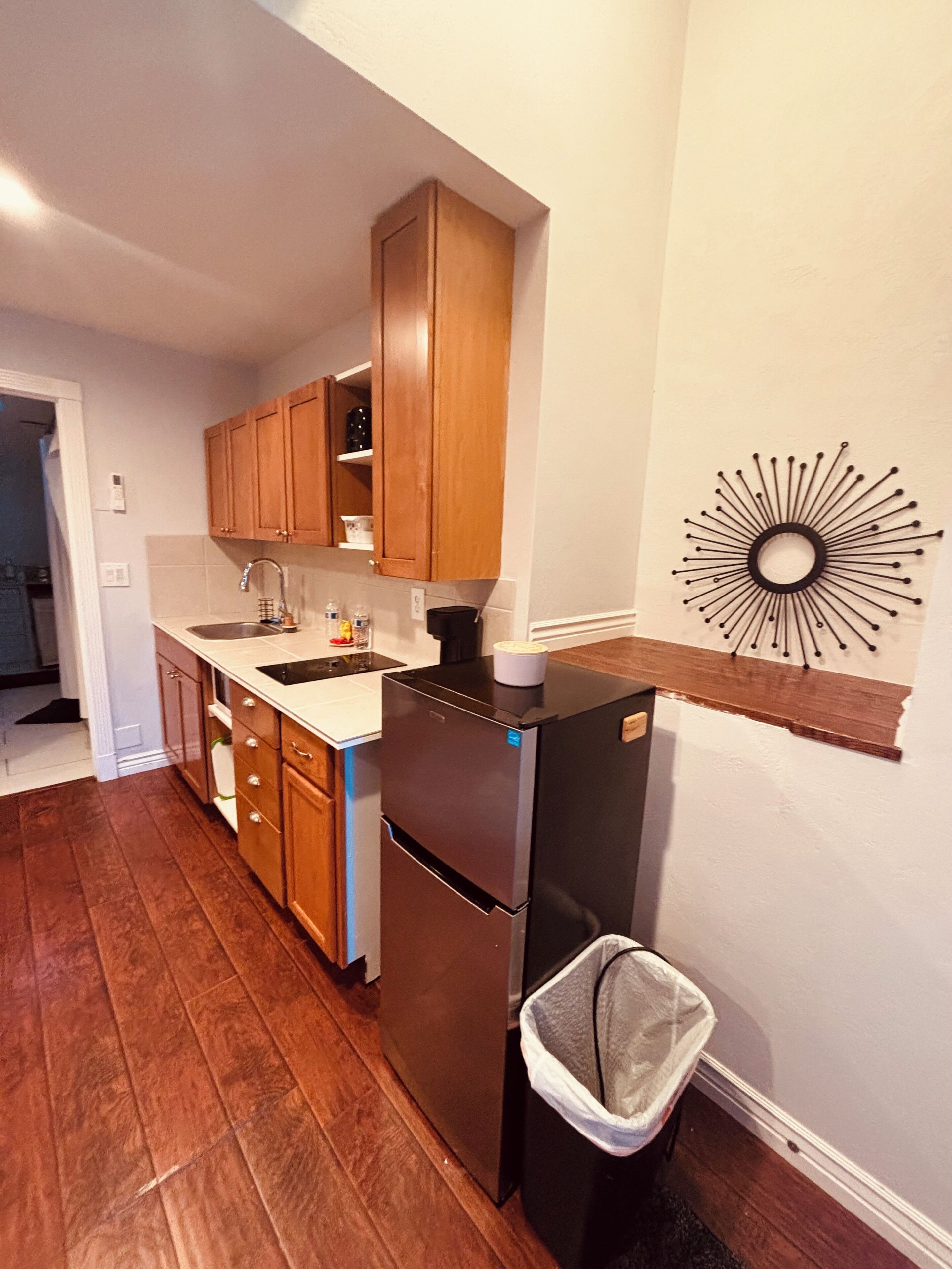 A kitchen with wooden cabinets, a stainless steel refrigerator, a sink, and a wall-mounted decorative item.