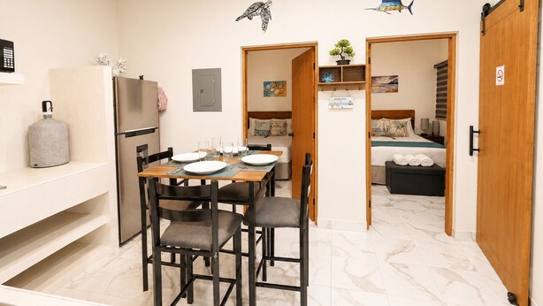 A compact hotel room with a bed, bedside table, and a small seating area. - CABO DOWNTOWN STUDIOS: 2BR Queen apt fully equipped Downtown steps to marina (Cabo San Lucas)