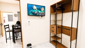 A room with a wooden desk, chairs, a television mounted on the wall, and a built-in wooden shelving unit. - CABO DOWNTOWN STUDIOS: 2BR Queen apt fully equipped Downtown steps to marina (Cabo San Lucas)