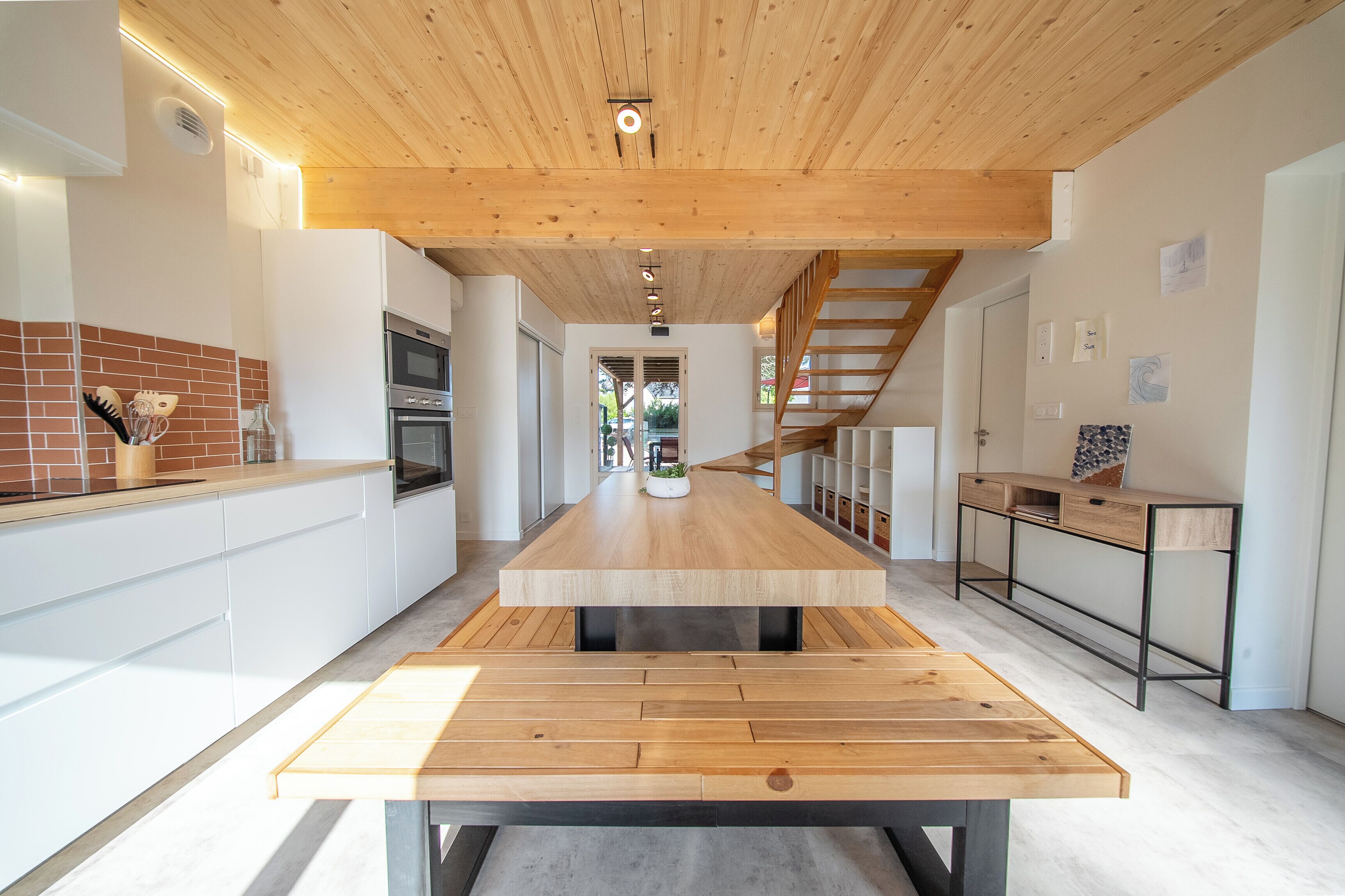 Eine moderne Küche mit Kochinsel, Holzboden und Blick ins Esszimmer.