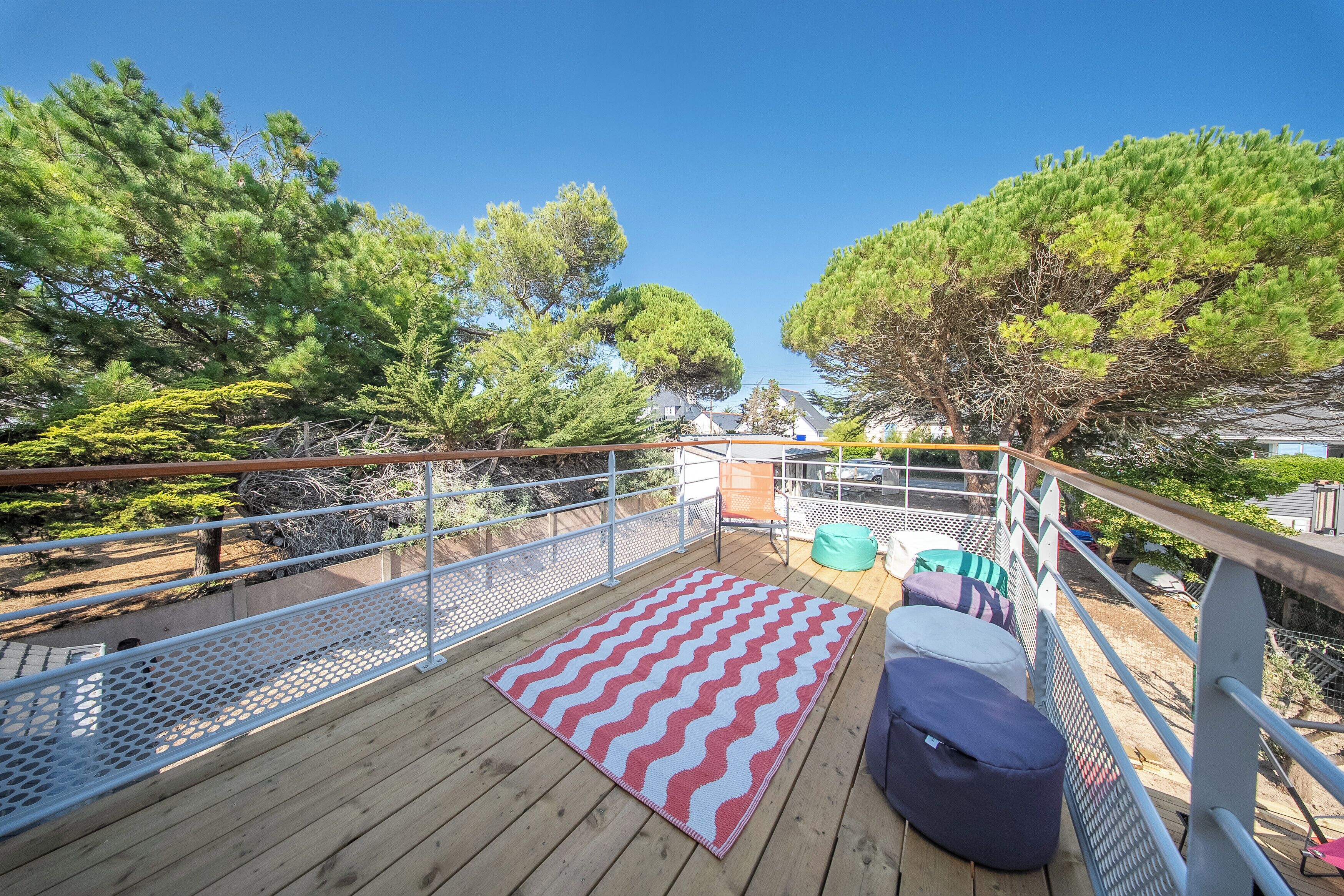 A wooden deck with a chevron-patterned rug, metal railings, and outdoor seating.